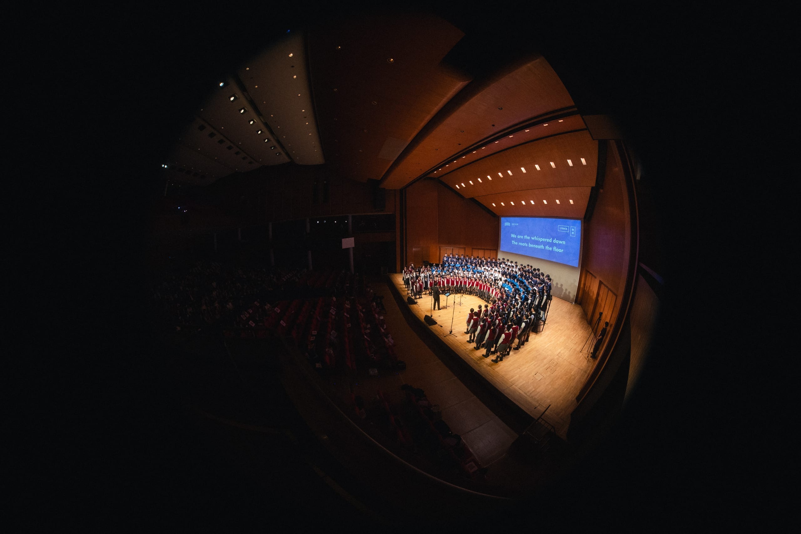 A massed choir performing together on a concert hall stage at an HKVC event