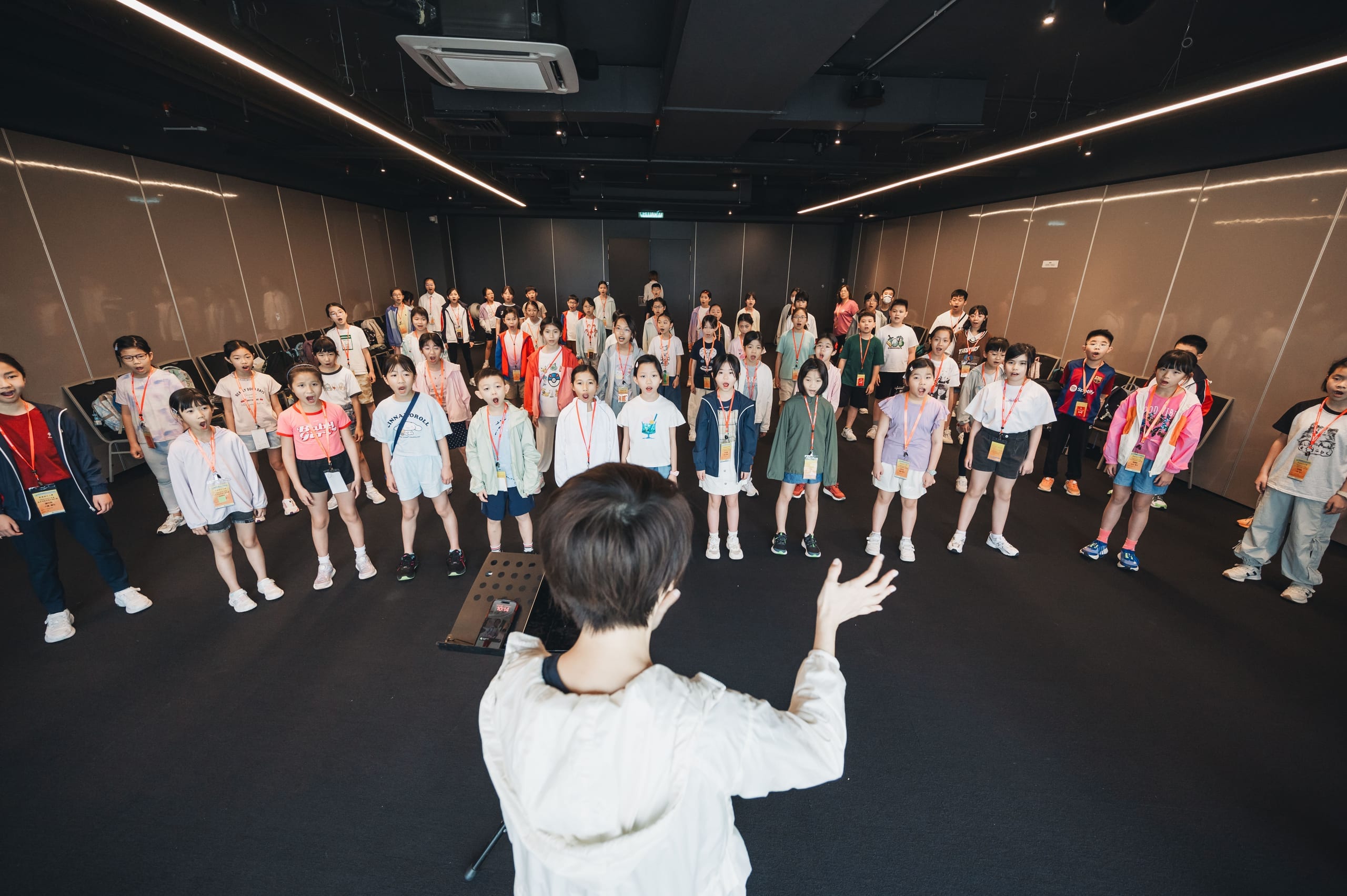 A conductor leads a large children's choir through a rehearsal during the Hong Kong–Malaysia school choir exchange in Kuala Lumpur