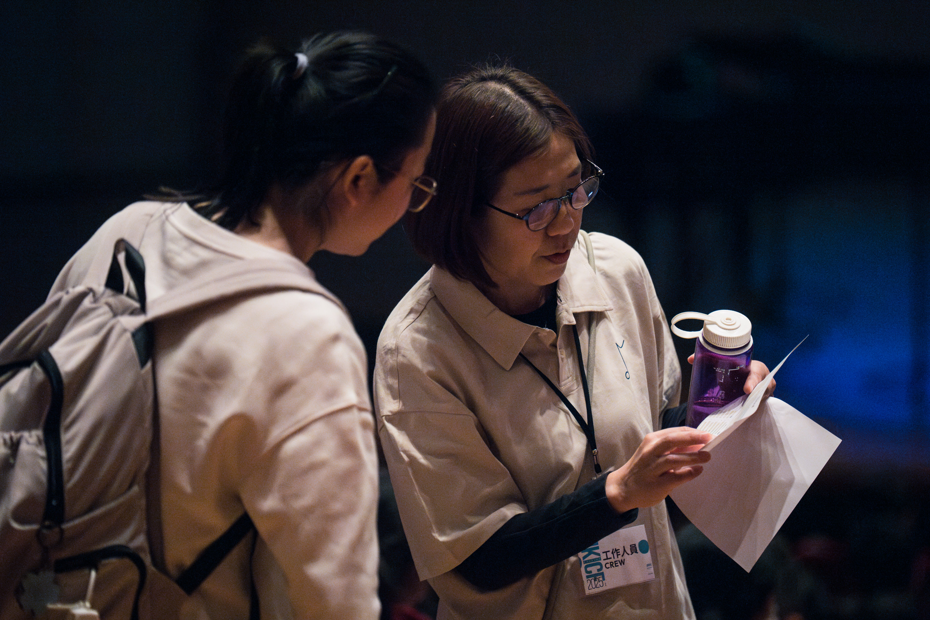 Two event crew members checking printed materials backstage