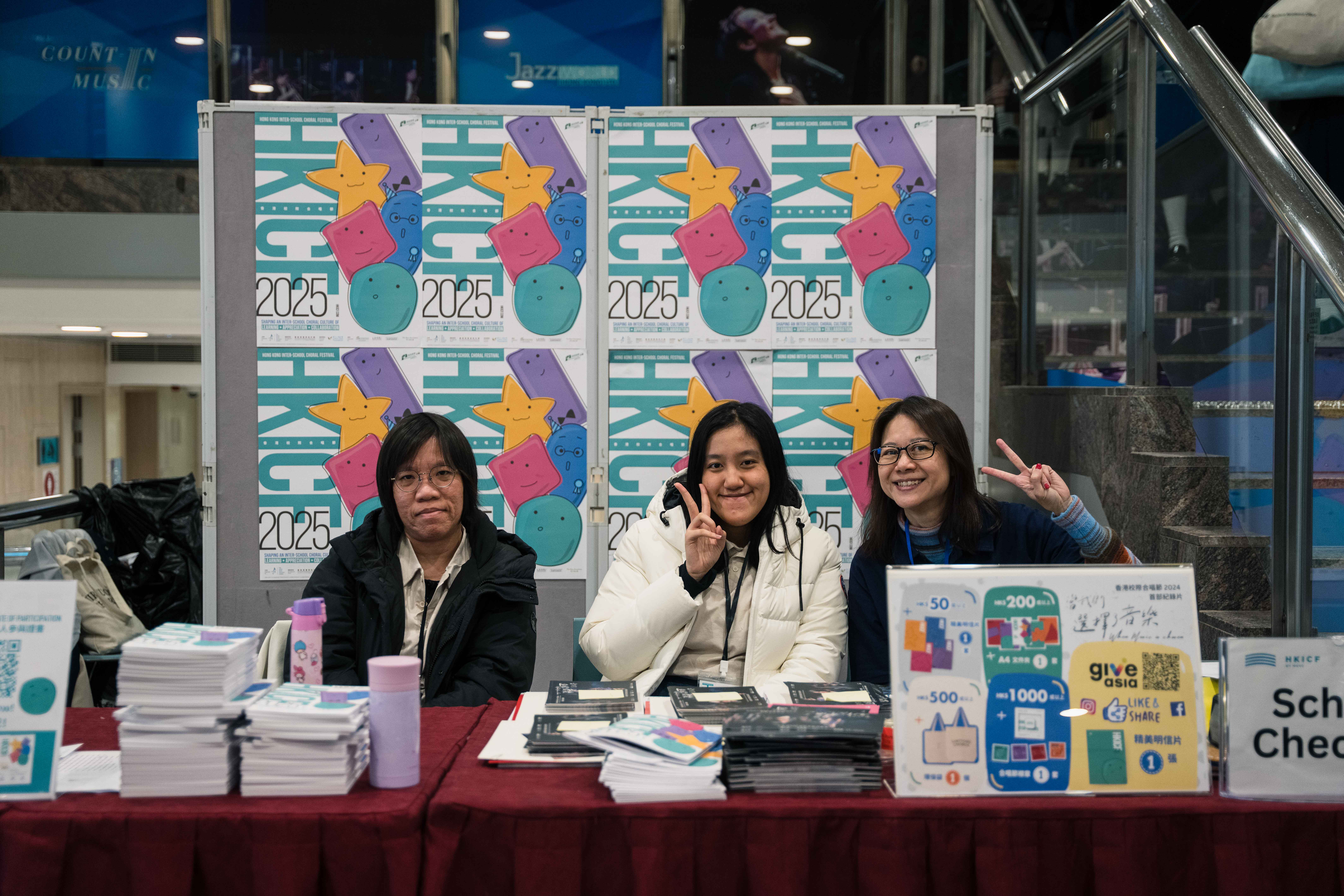 Three volunteers at an HKICF school check-in desk
