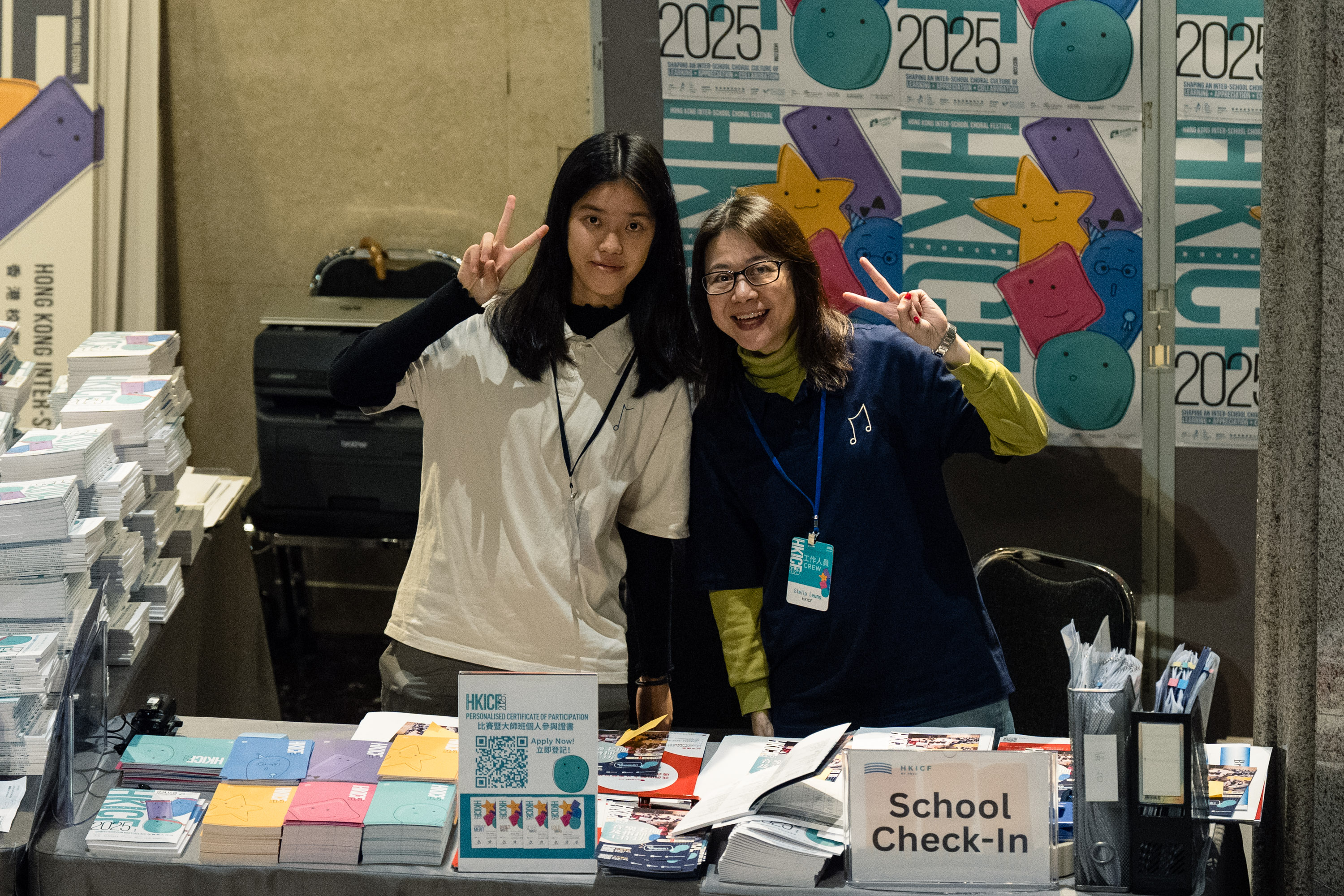 Two volunteers greeting visitors at an HKICF school check-in desk
