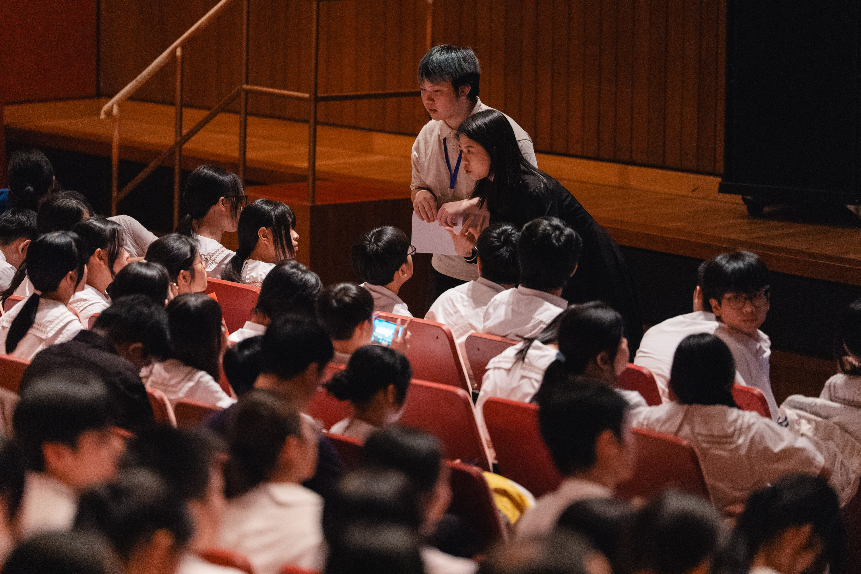 Event team members coordinating with student performers in an auditorium
